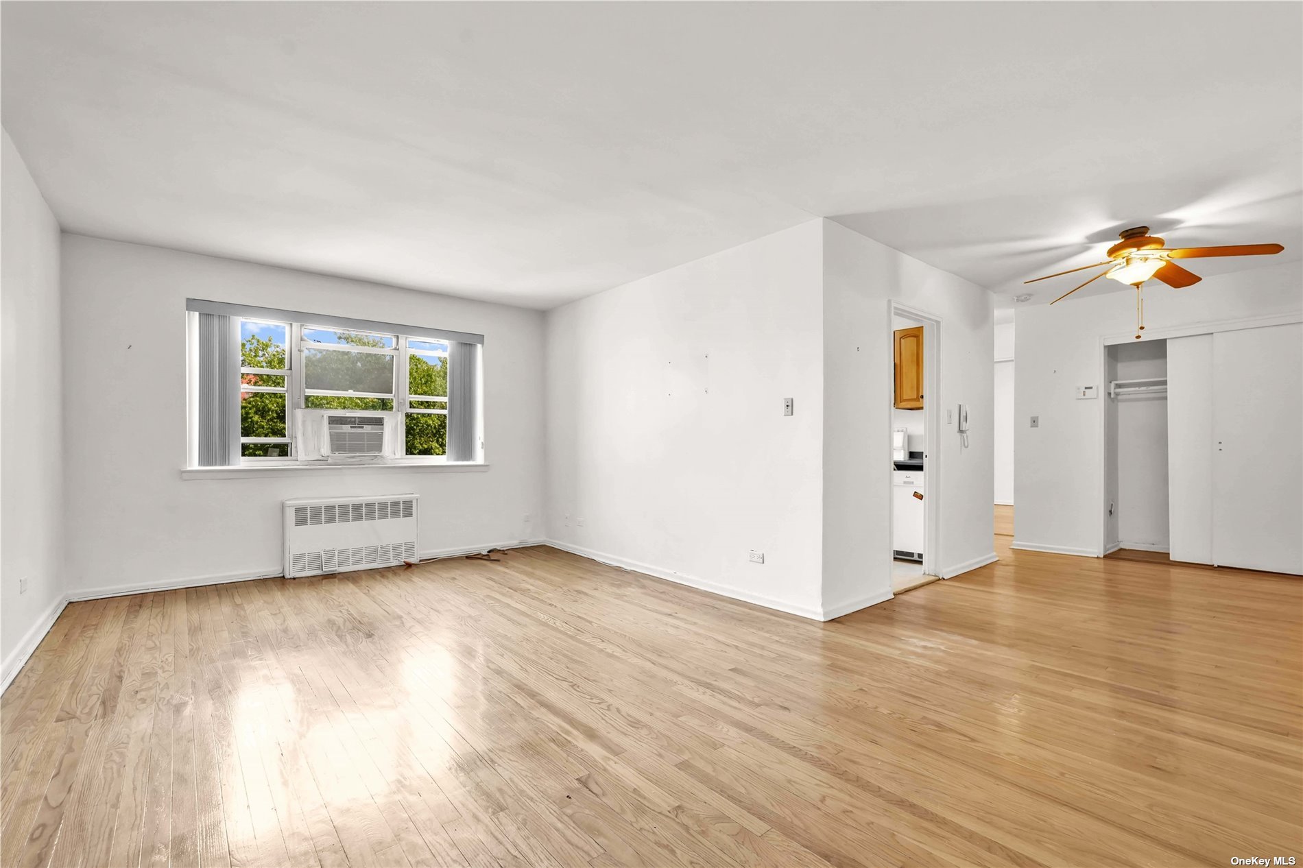 a view of an empty room with a window and wooden floor