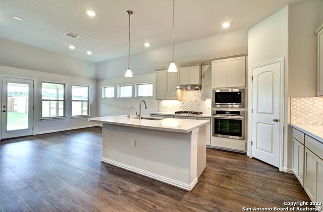 a large kitchen with granite countertop a large counter top a sink stainless steel appliances and cabinets