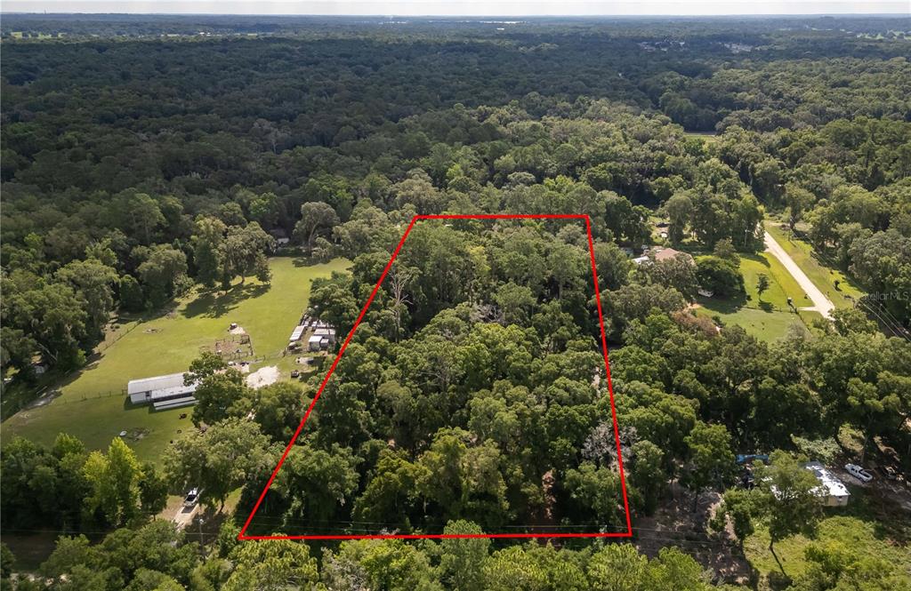 an aerial view of residential house with outdoor space and trees all around