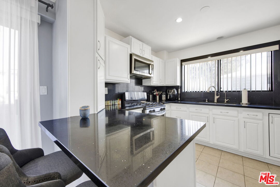 a large kitchen with granite countertop a sink and white cabinets