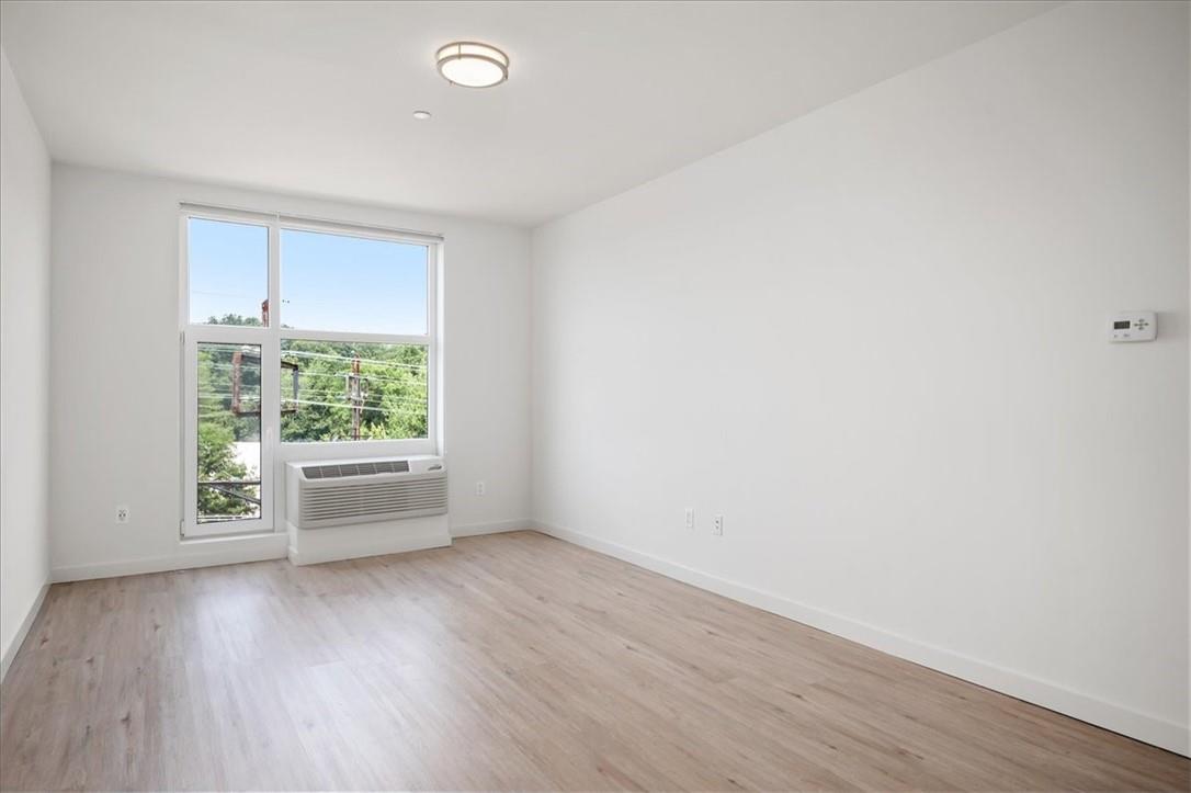 Spare room with light wood-type flooring and an AC wall unit