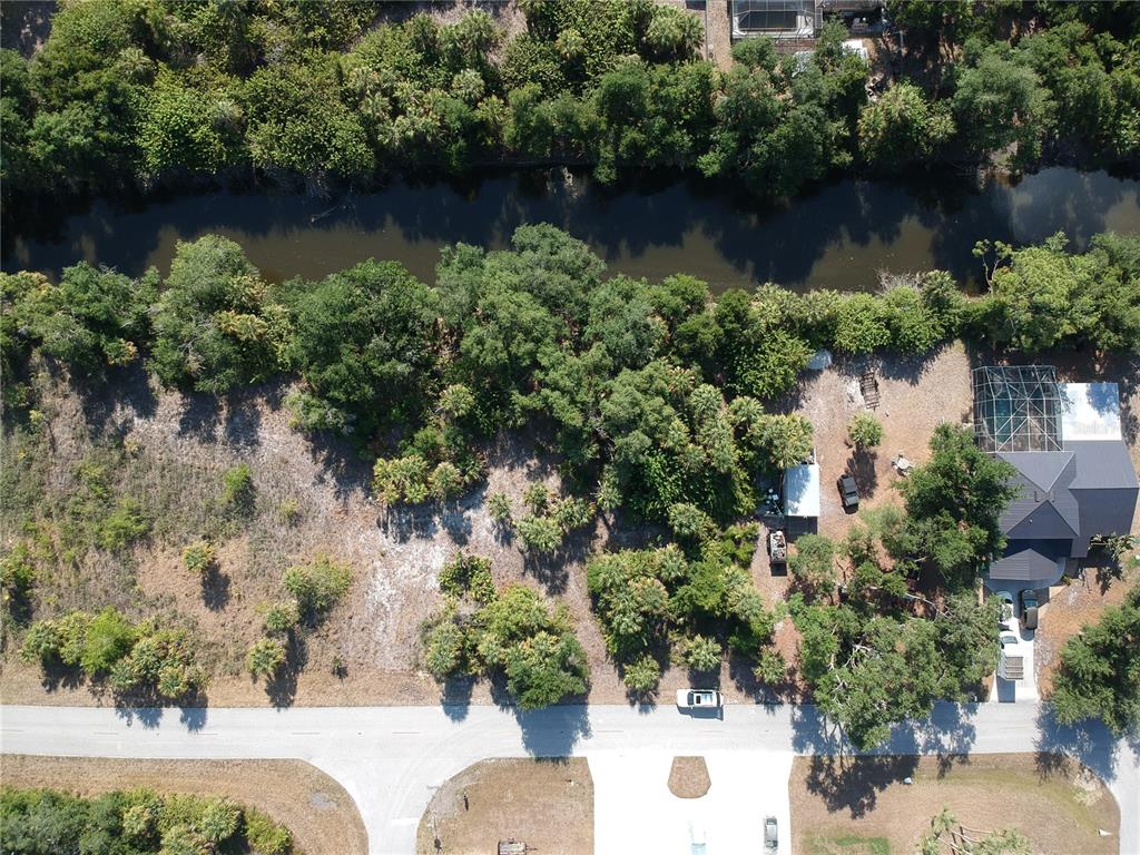 an aerial view of a house with outdoor space lake and trees all around