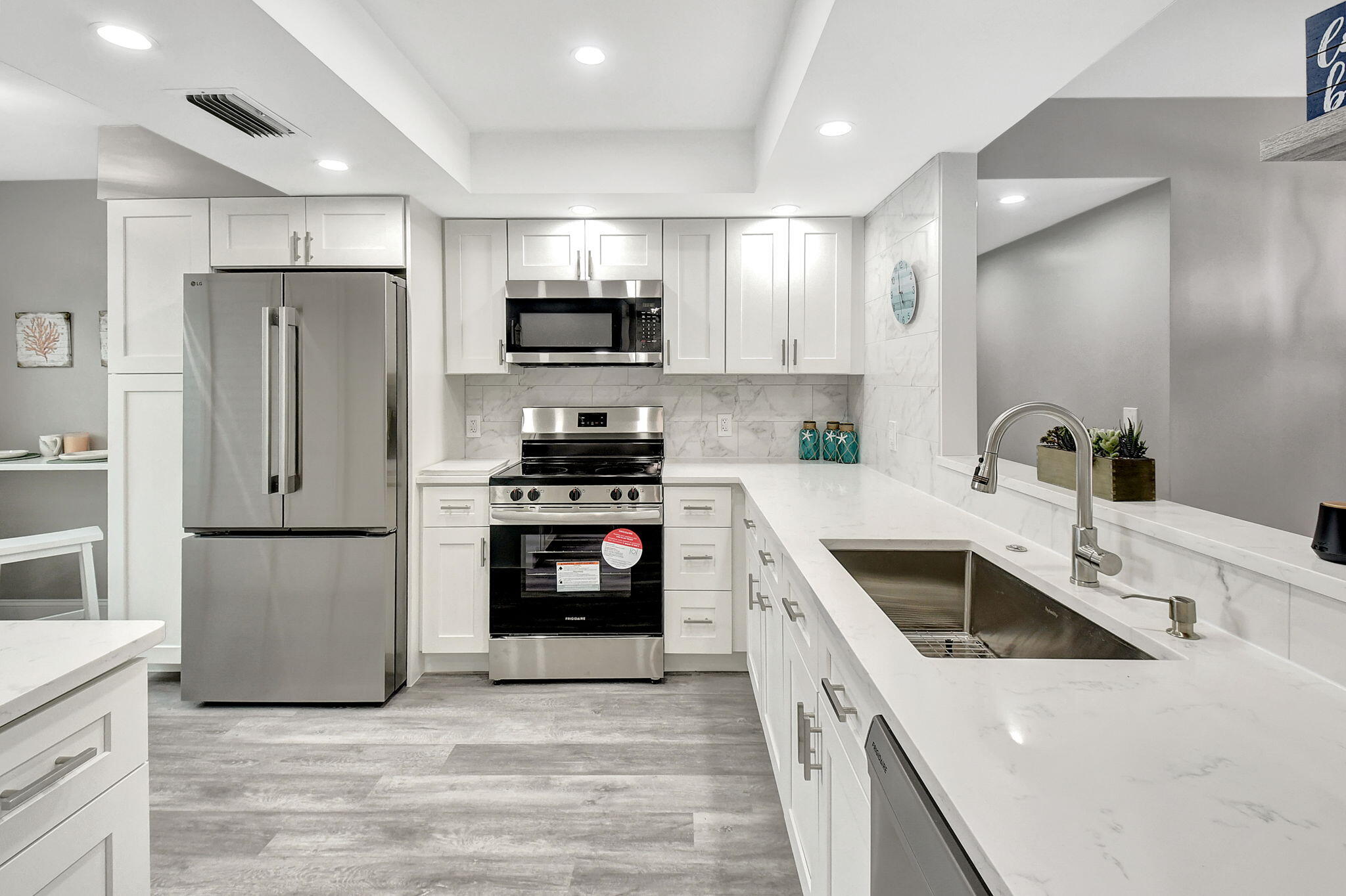 a kitchen with kitchen island a refrigerator sink and white cabinets