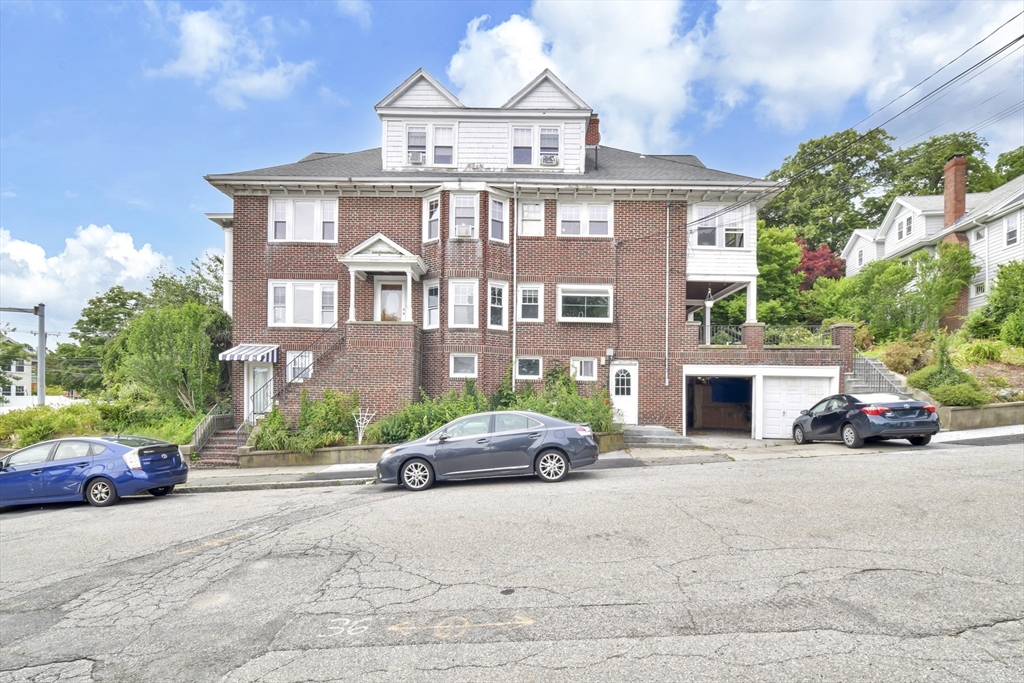 a front view of a house with a garden and parking