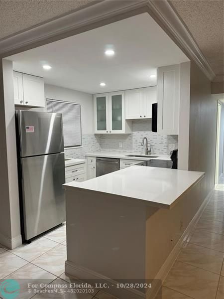 a kitchen with stainless steel appliances granite countertop a refrigerator a sink and a stove