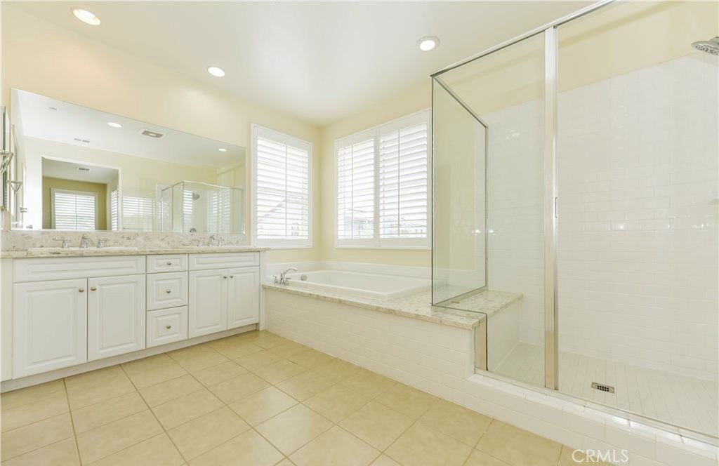 a spacious bathroom with a granite countertop sink a toilet mirror and shower