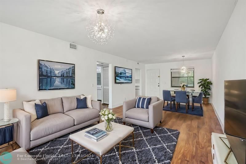 a living room with furniture a dining table and a chandelier