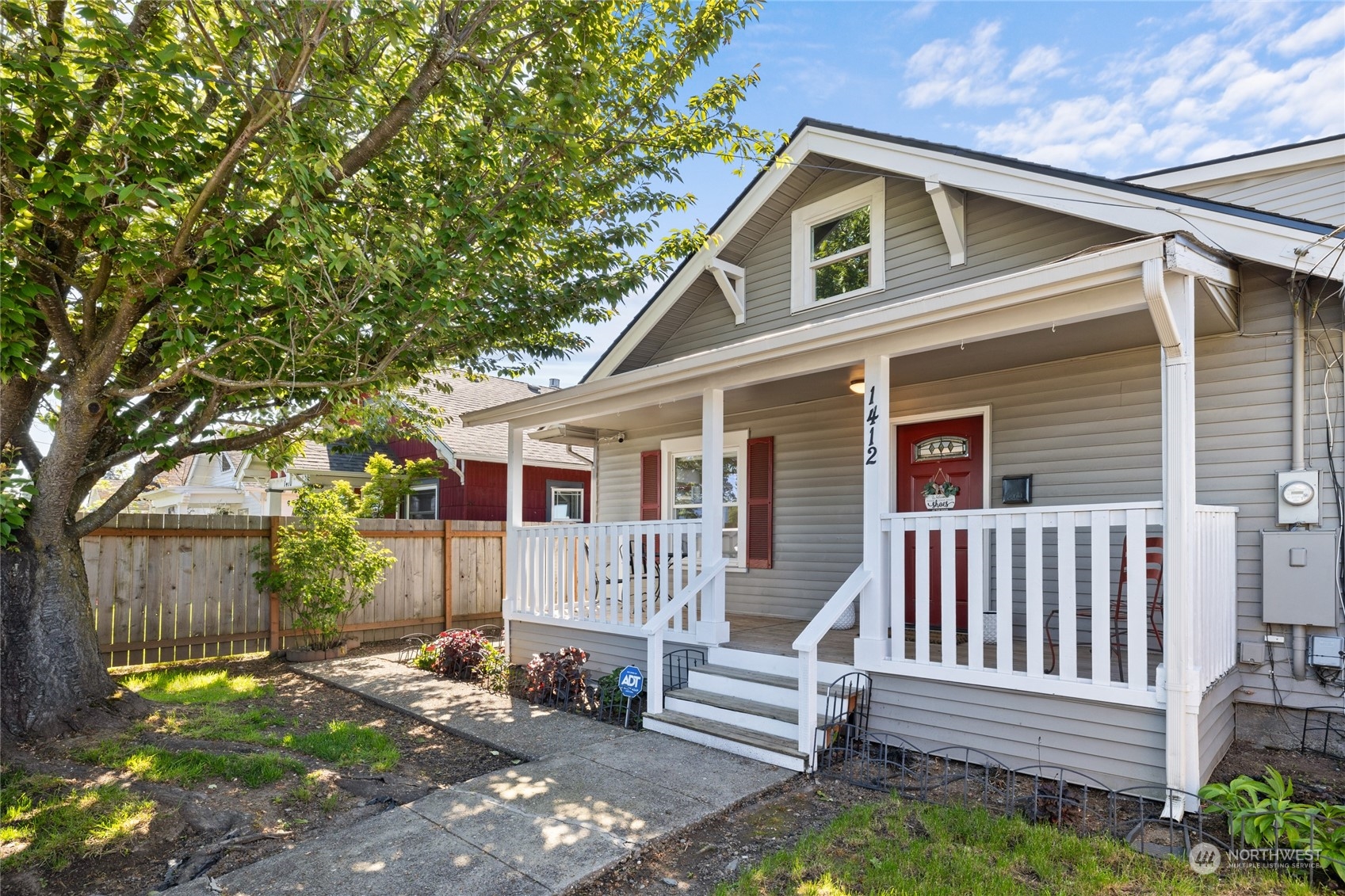 a view of a wooden house with a small yard and wooden fence