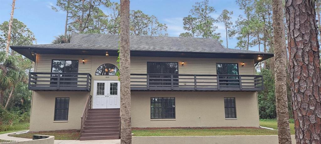 View of front of home with a balcony and a front yard