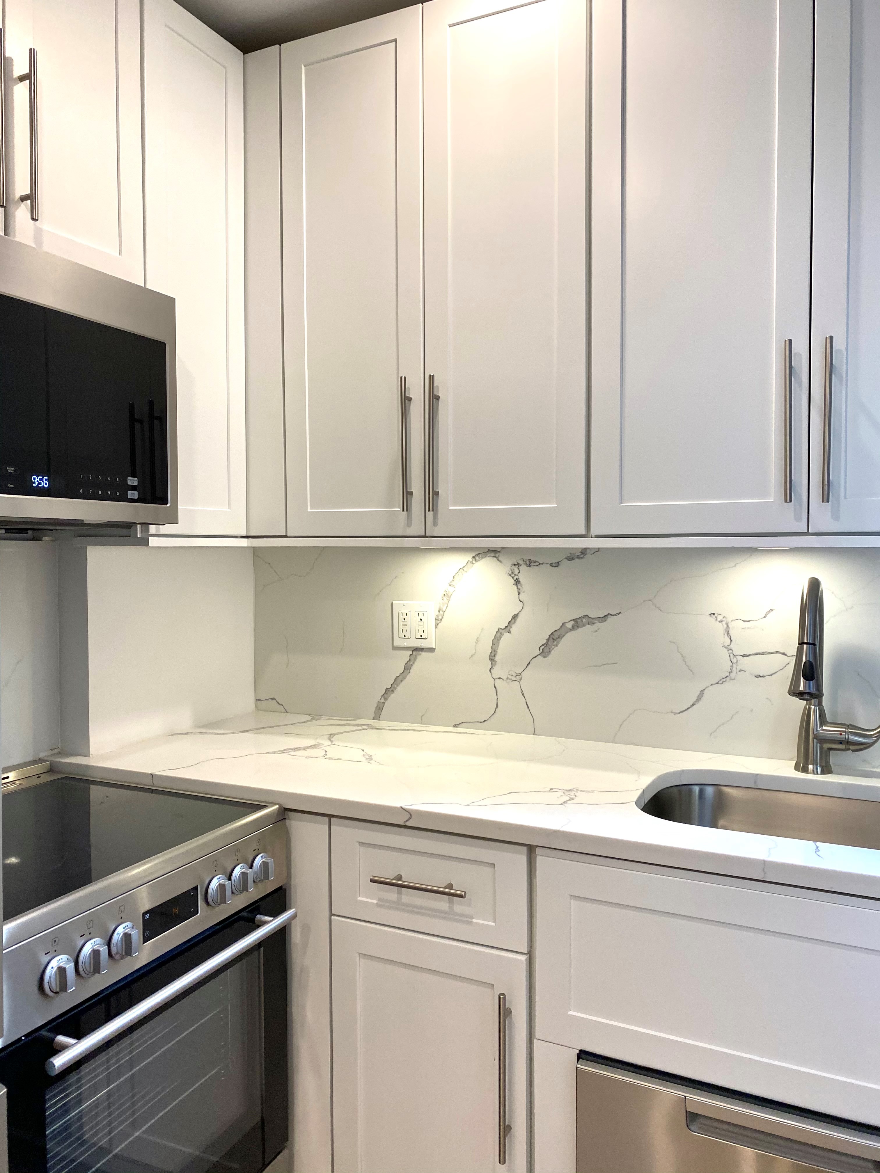 a kitchen with granite countertop a sink a stove and a microwave