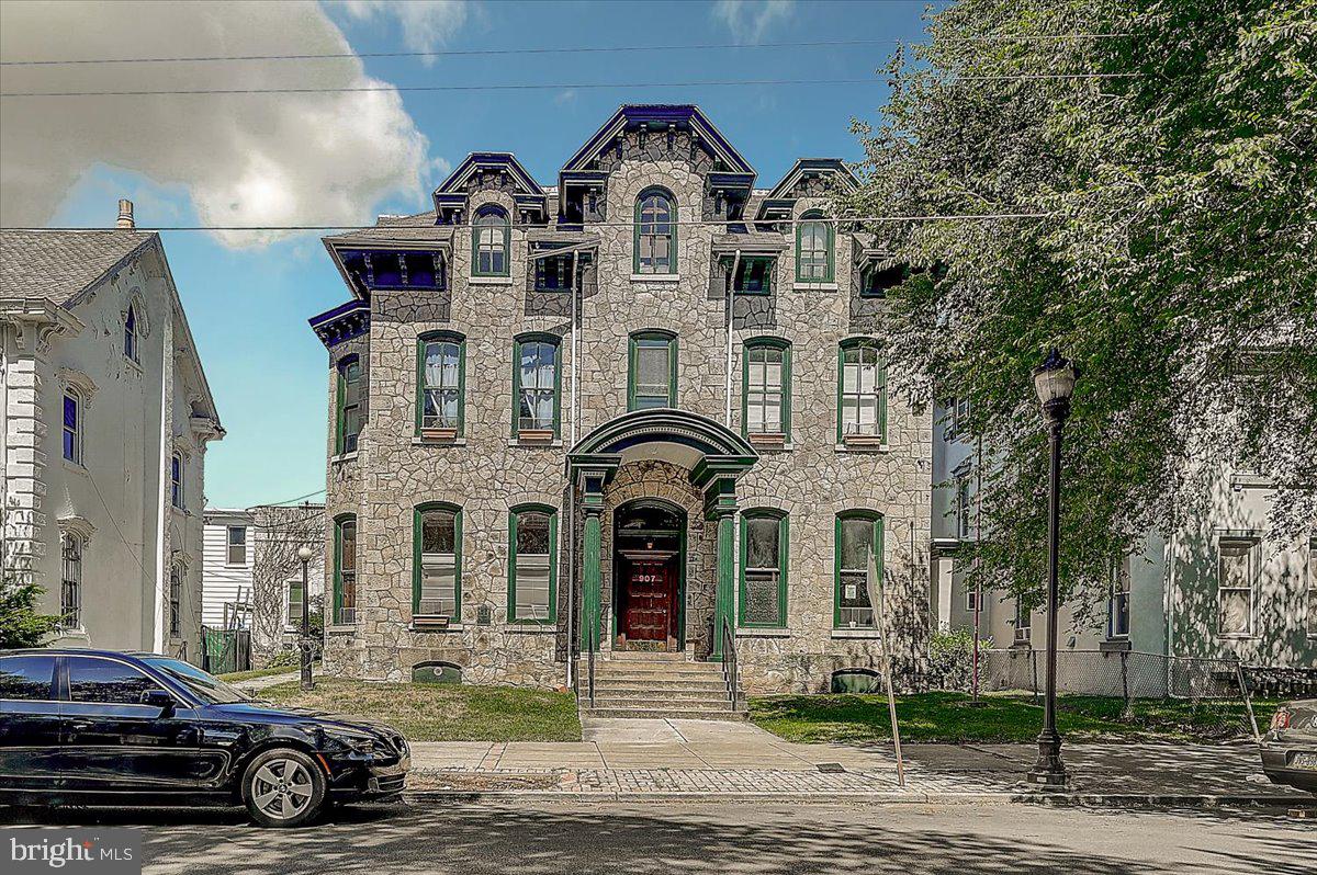 a view of a big house with a cars park