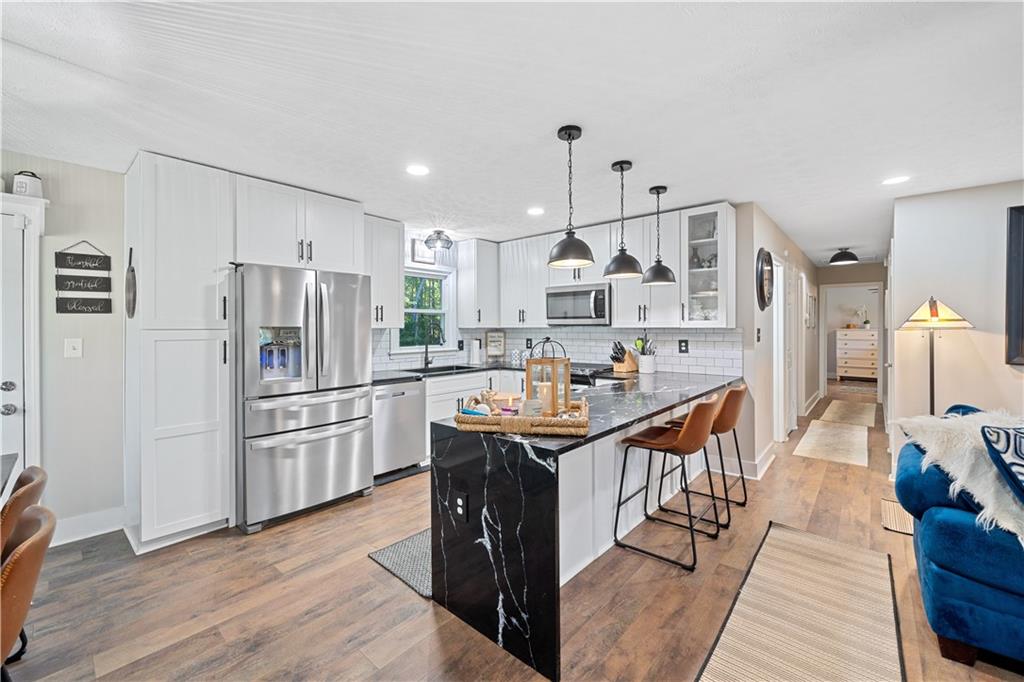 a kitchen with stainless steel appliances kitchen island granite countertop a table chairs refrigerator and sink