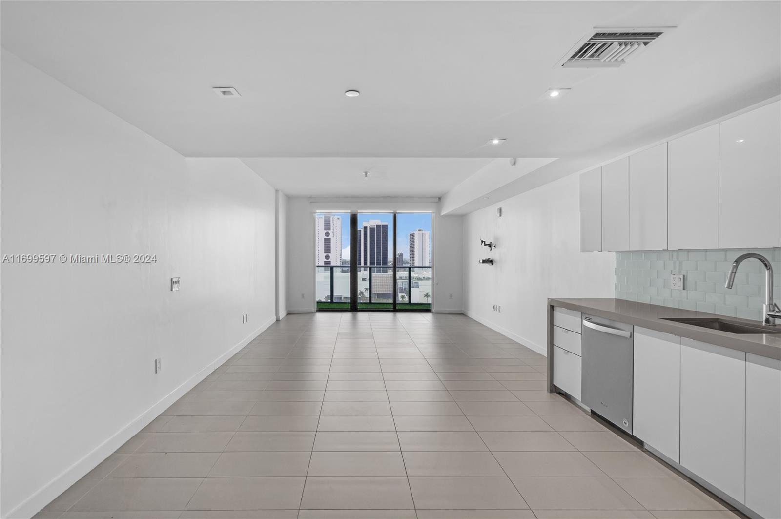 a view of a kitchen with a sink and dishwasher a refrigerator with white cabinets