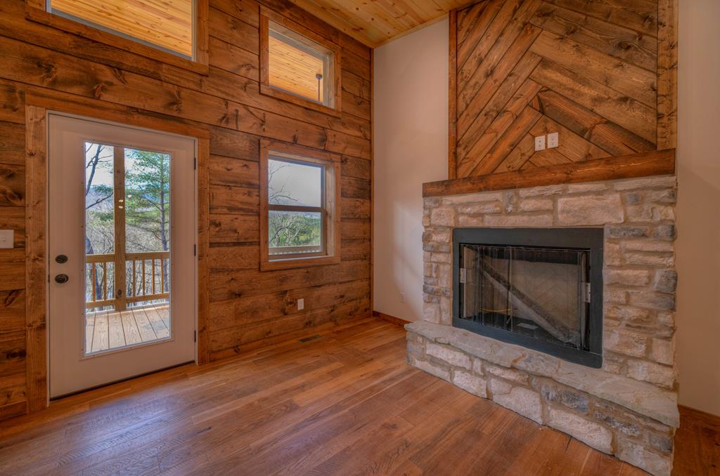 an empty room with wooden floor fireplace and windows