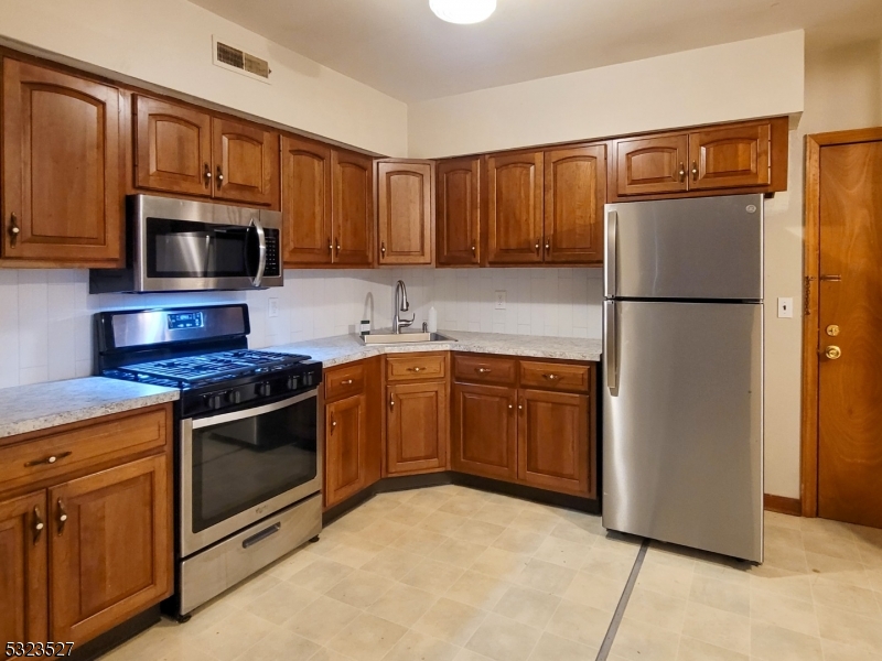 a kitchen with granite countertop a refrigerator stove and microwave