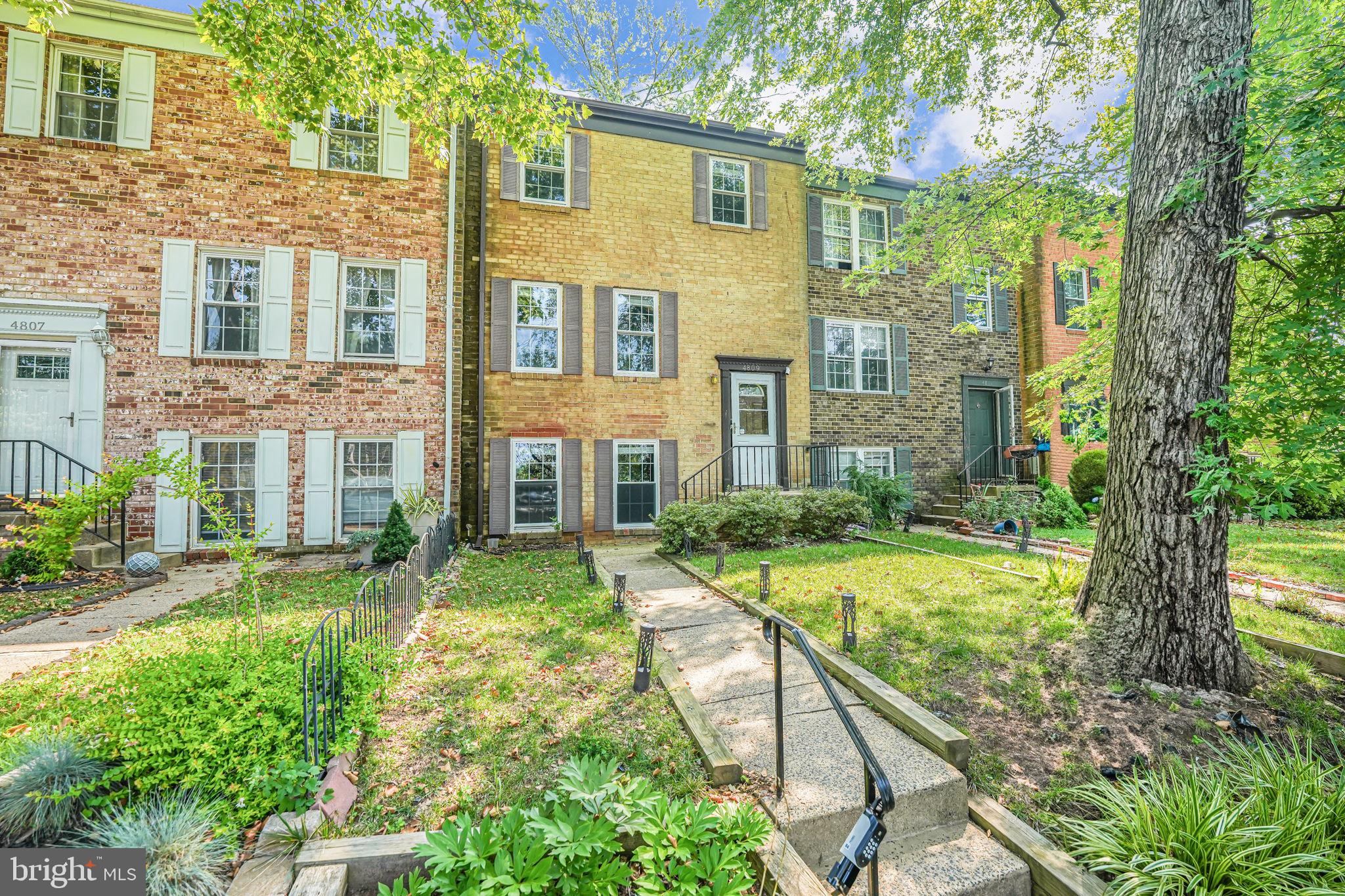 a view of a brick house with a yard and plants