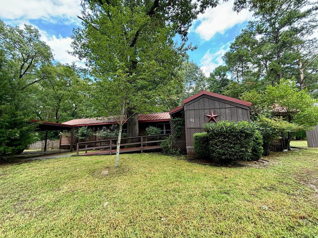 a view of a house with a yard plants and large tree