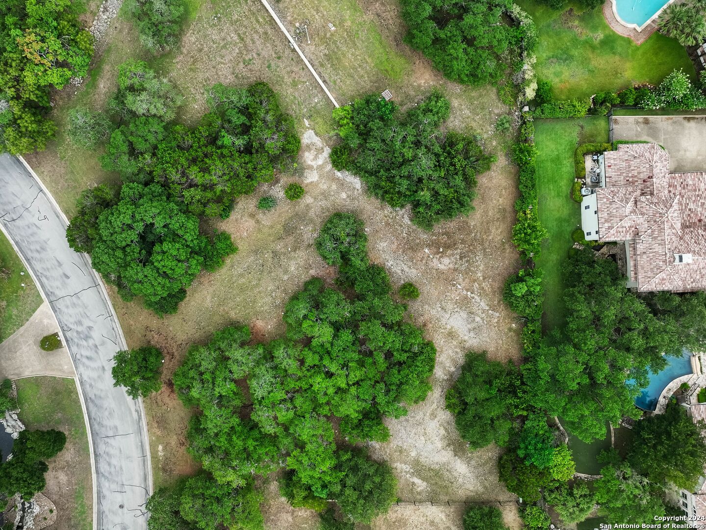 an aerial view of a house with a yard and trees all around