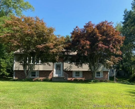 a front view of a house with a garden and trees