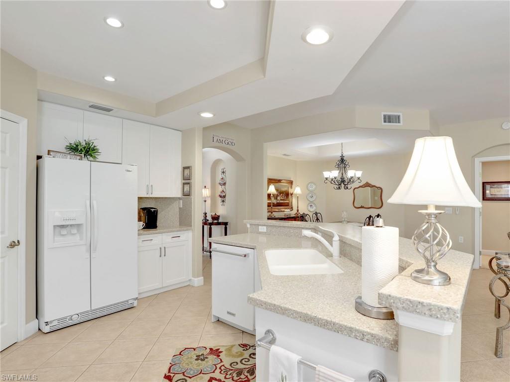 Open Concept Kitchen with white cabinets, granite countertops, white appliances, and decorative light fixtures