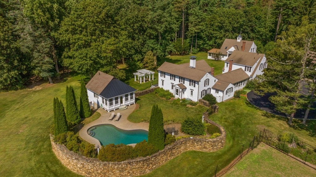 an aerial view of a house with swimming pool and large trees