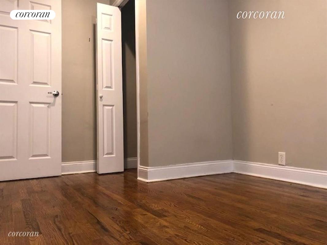 a view of an empty room with wooden floor and closet