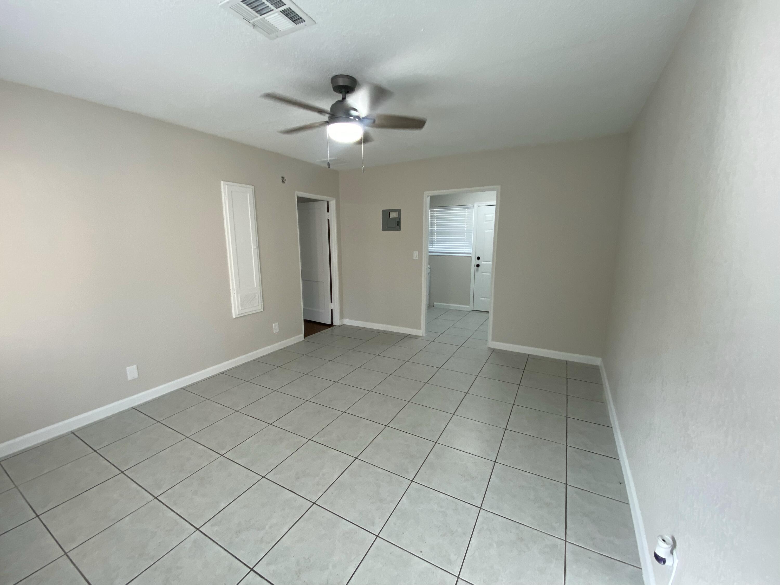 a view of an empty room and chandelier fan