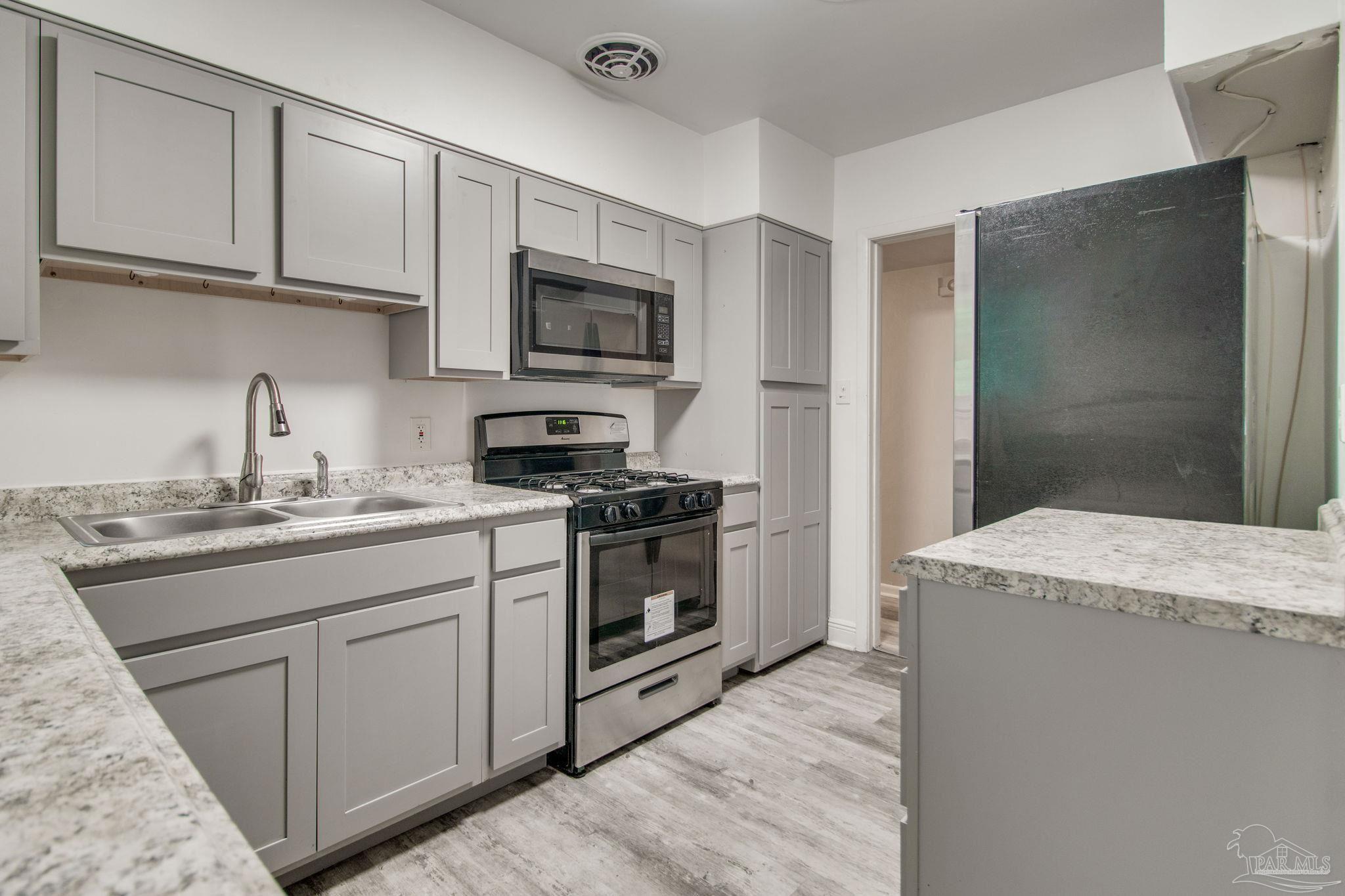 a kitchen with stainless steel appliances granite countertop a sink and a stove top oven