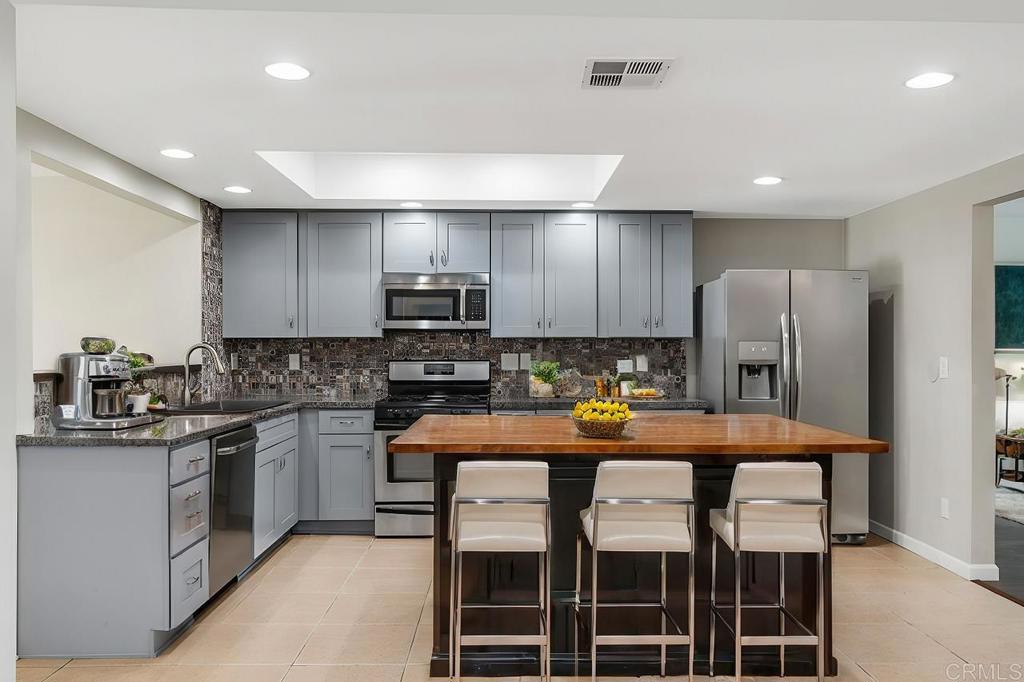 a kitchen with stainless steel appliances granite countertop a stove top oven a refrigerator and white cabinets