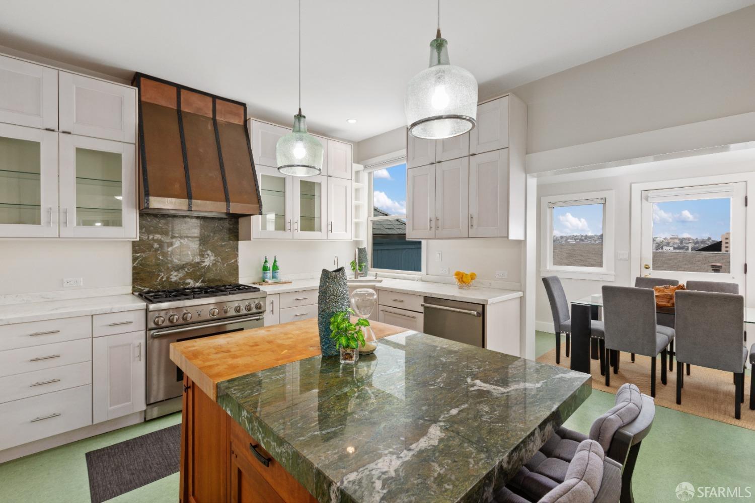 a kitchen with kitchen island granite countertop a stove a sink a dining table and chairs