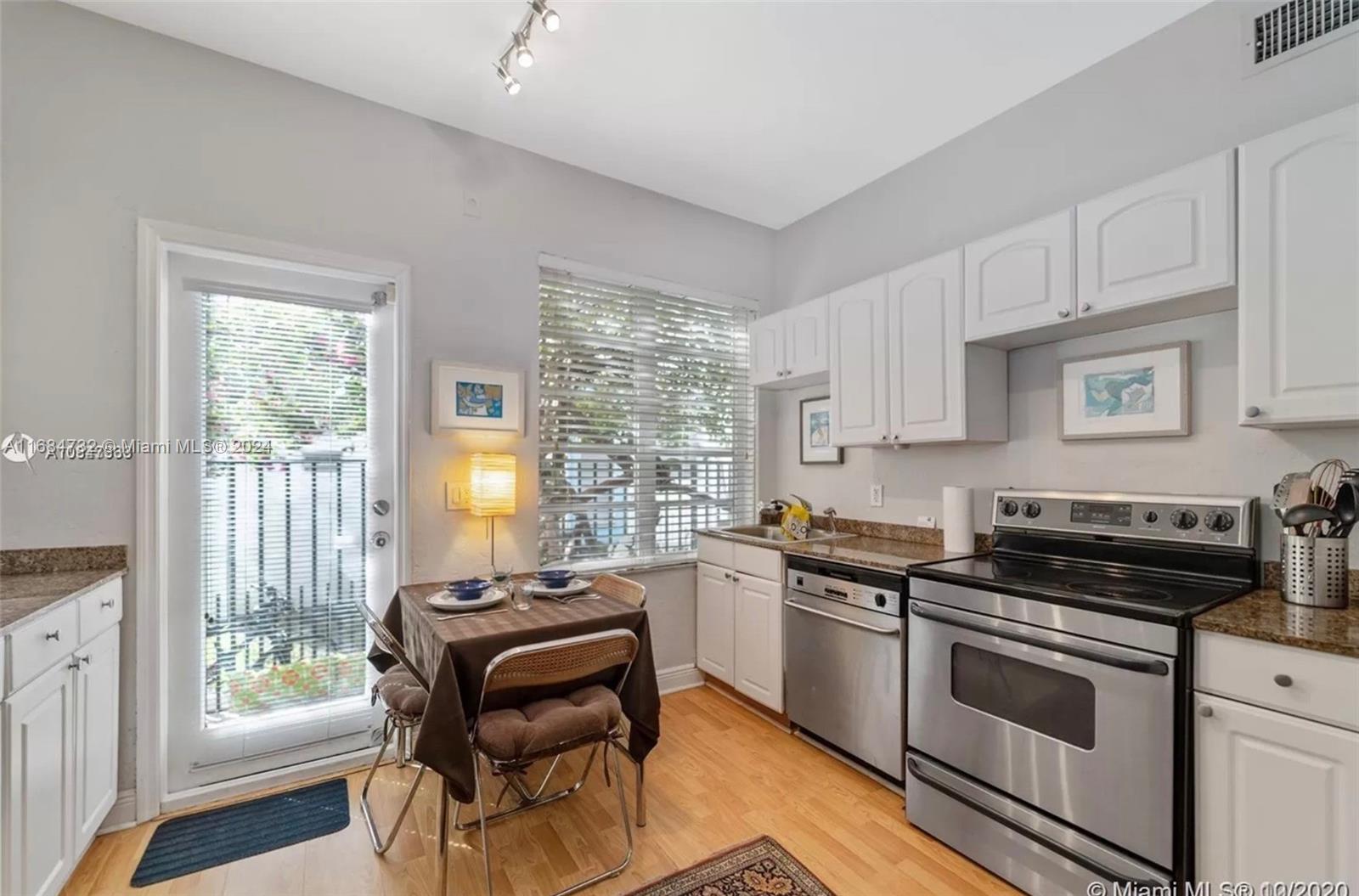 a kitchen with granite countertop a stove a sink and white cabinets