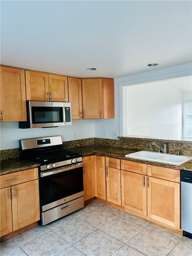 a kitchen with granite countertop a stove a sink and a microwave