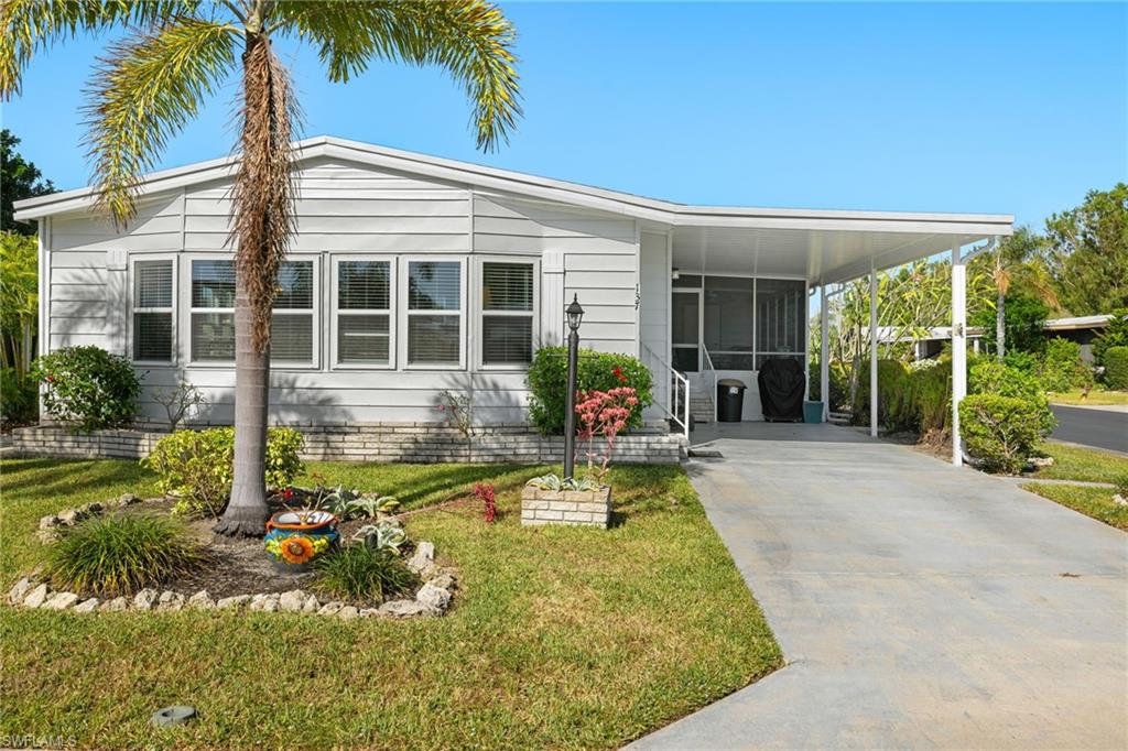 Manufactured / mobile home with a front yard and a carport