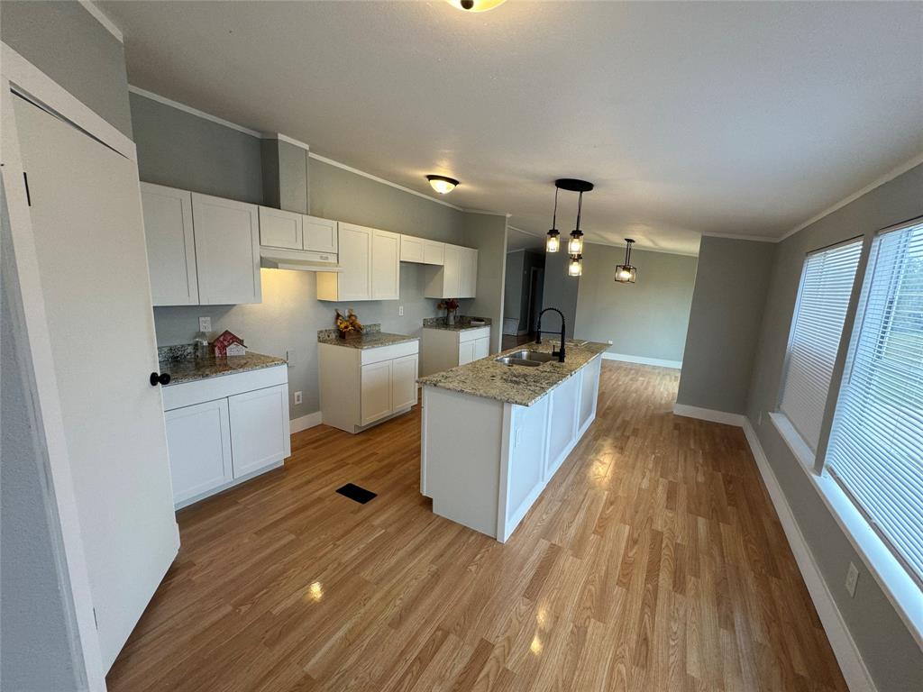 a kitchen with a sink wooden floor and stainless steel appliances