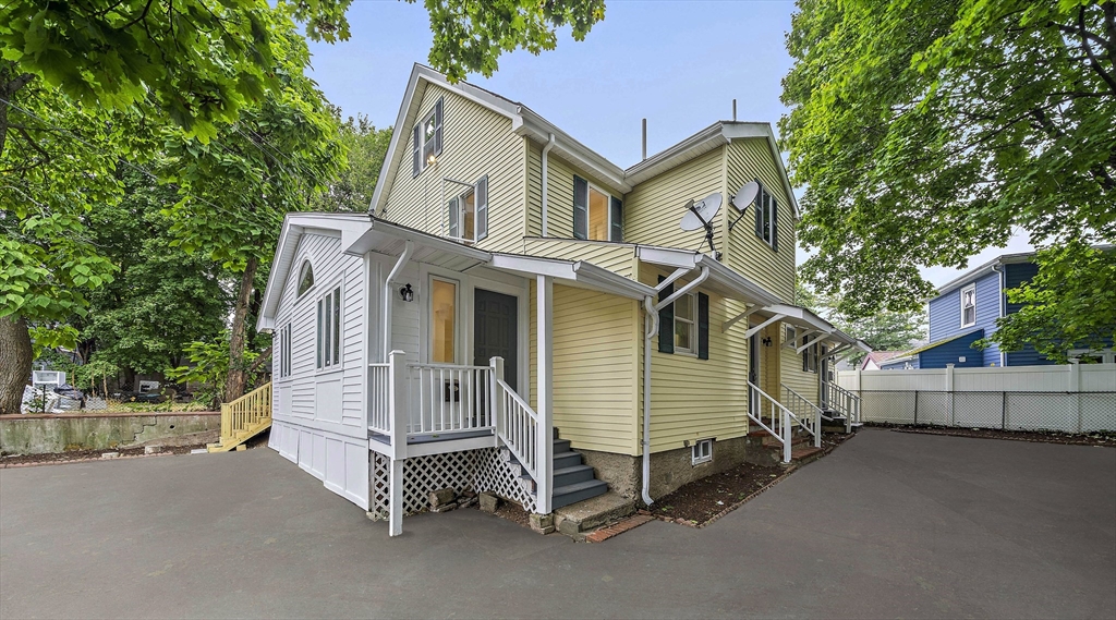 a white house with a large tree and wooden fence