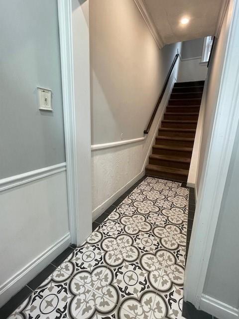 Stairway with tile patterned flooring and ornamental molding