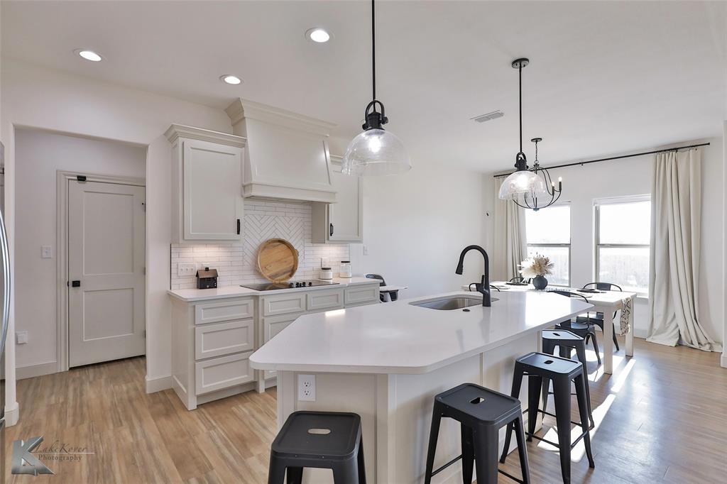 a kitchen with kitchen island a dining table chairs and white cabinets