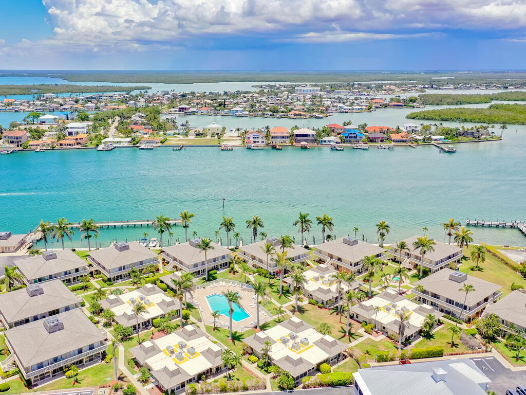 an aerial view of ocean and residential houses with outdoor space