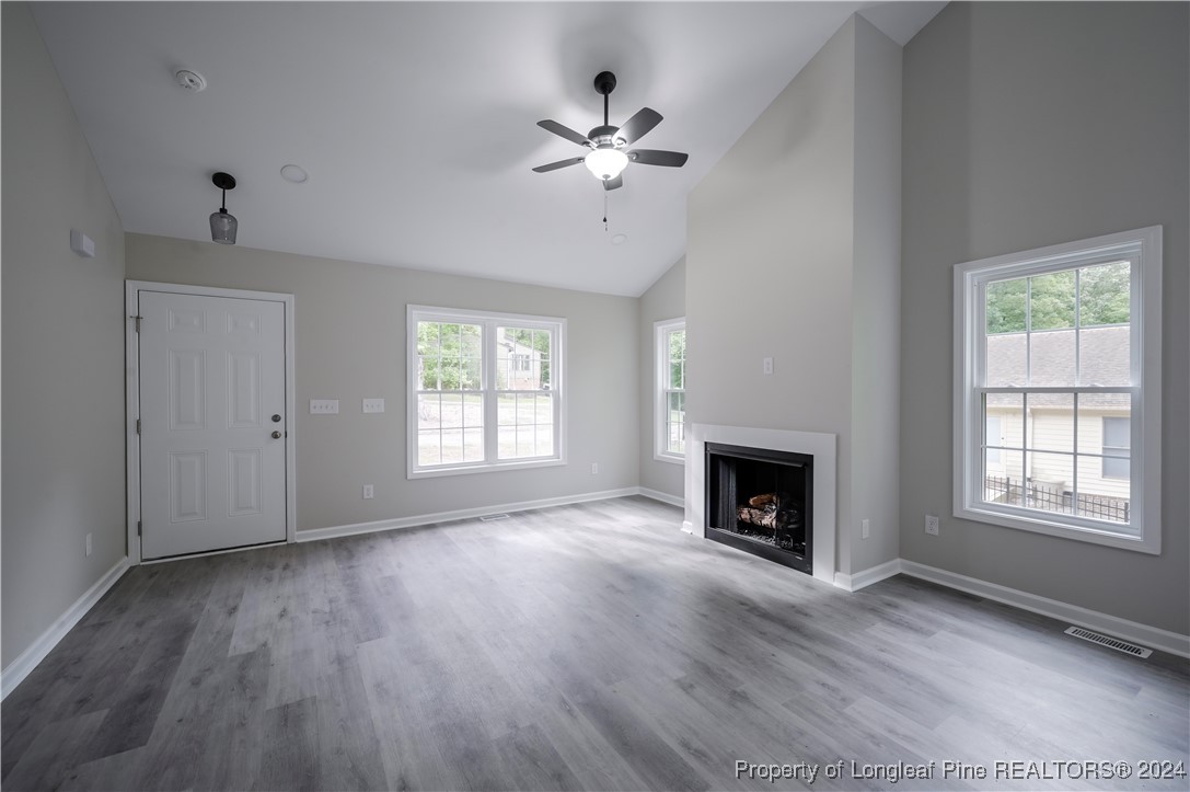 an empty room with windows fireplace and wooden floor