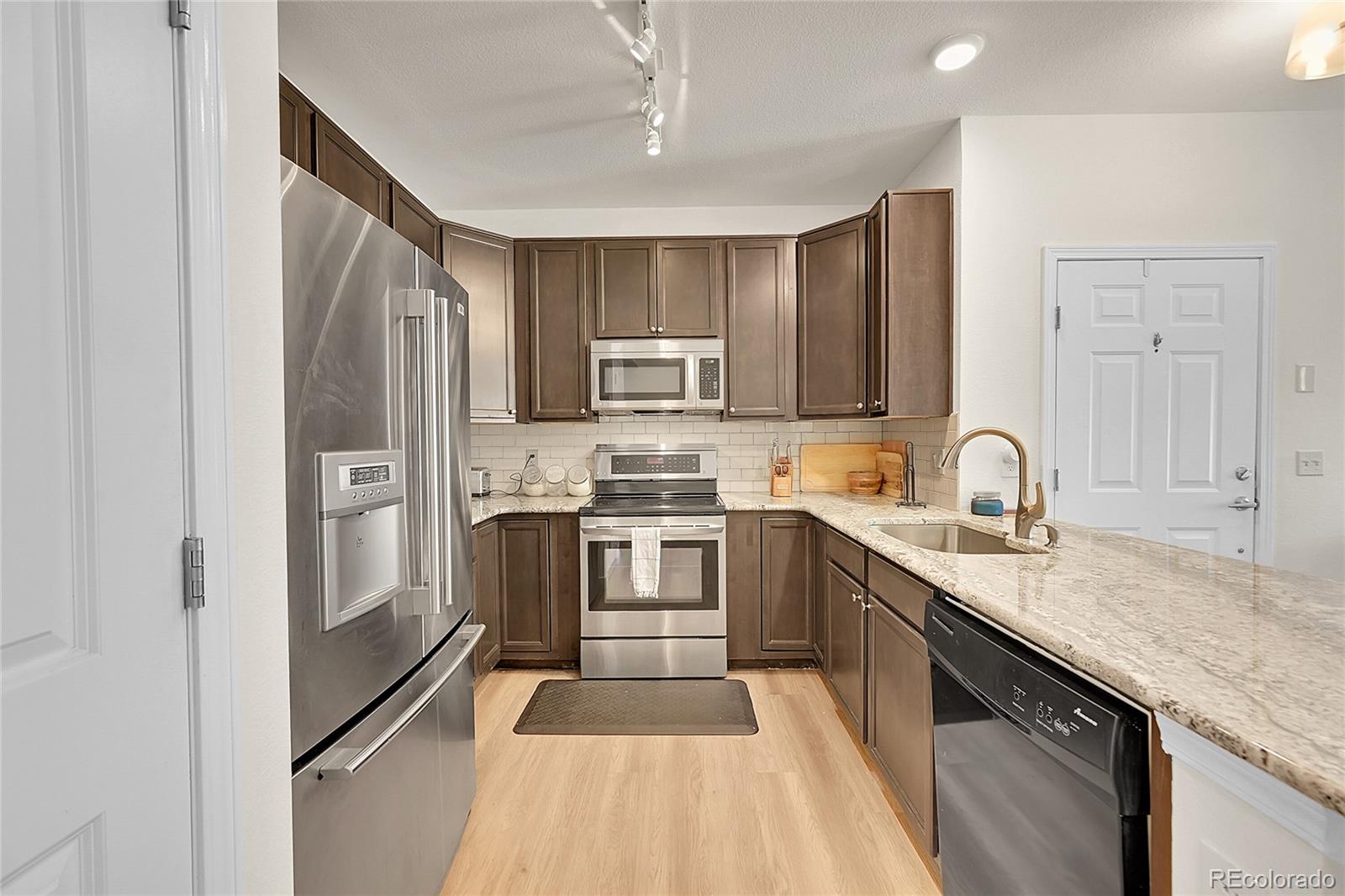 a kitchen with stainless steel appliances granite countertop a refrigerator and a stove top oven