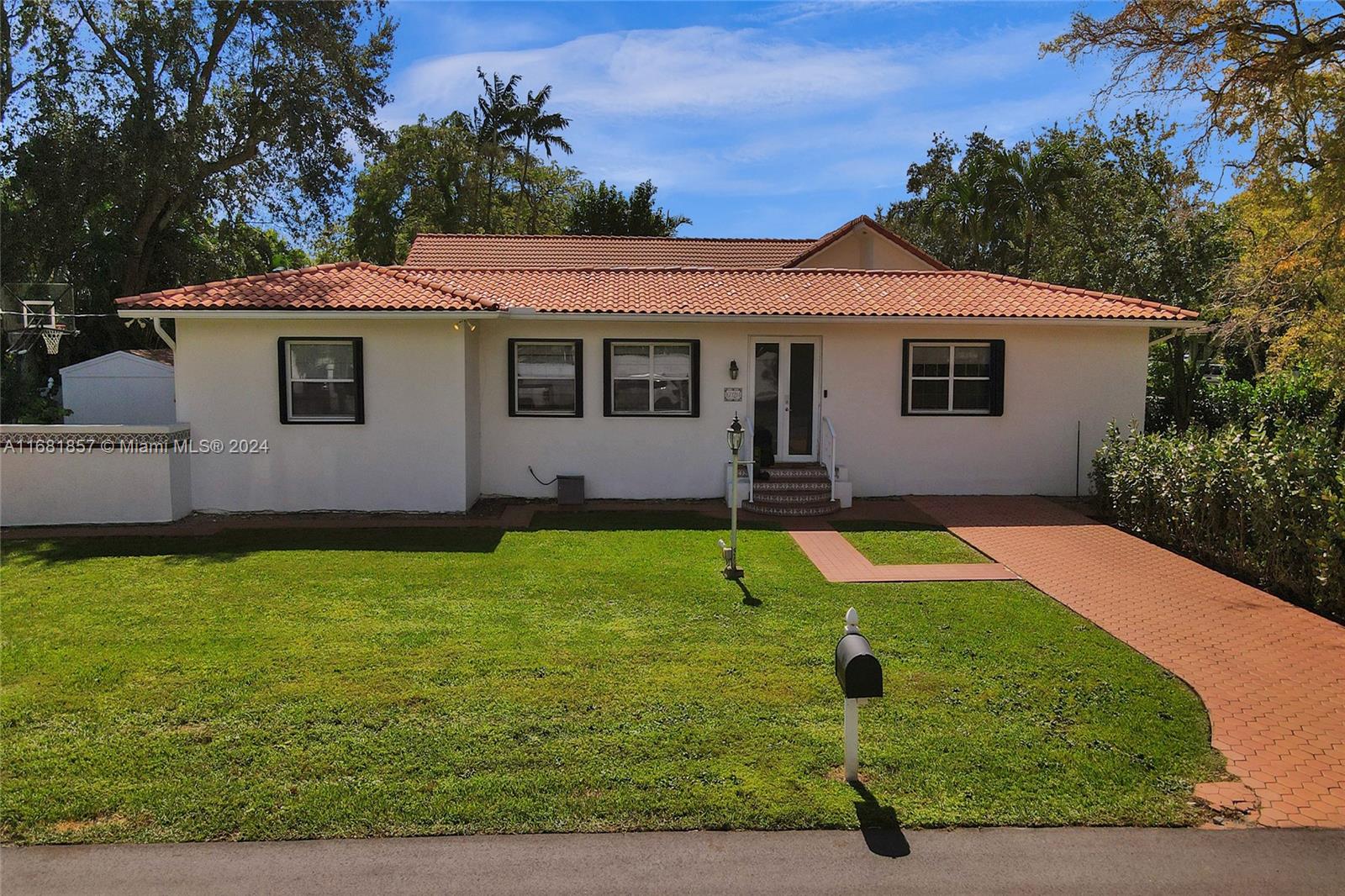 a front view of house with yard and trees in the background