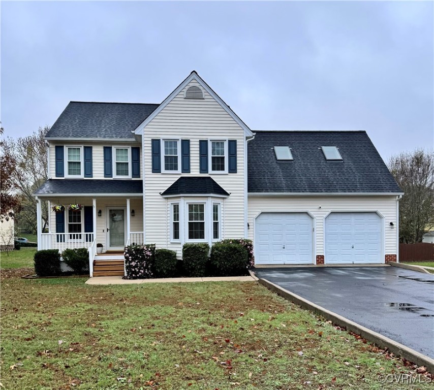 View of front facade with covered porch, a garage,