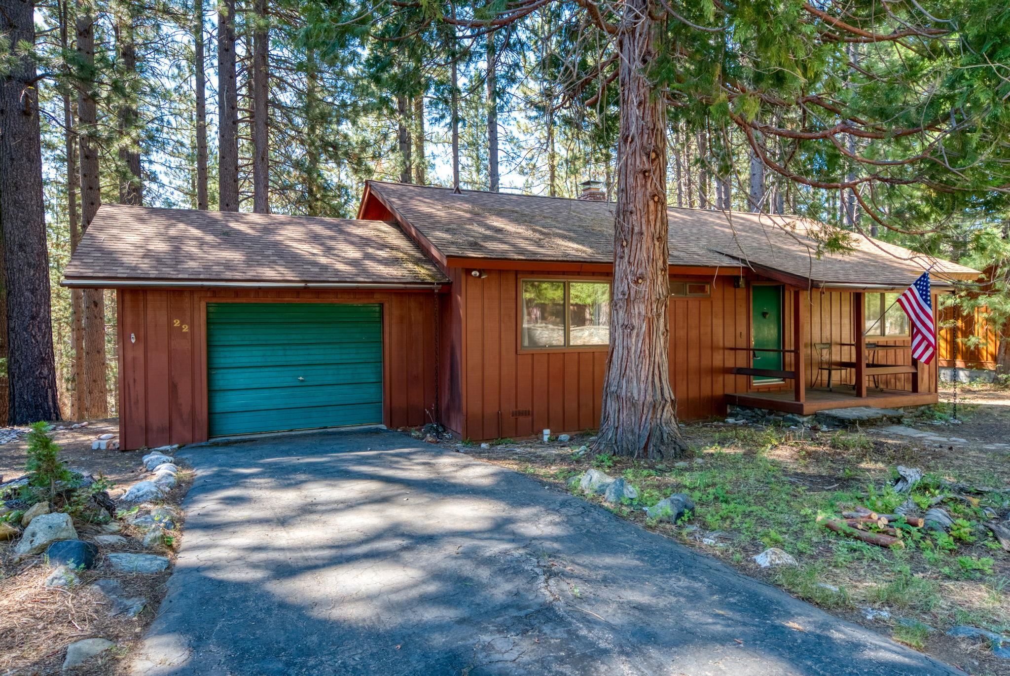 a view of a house with a small yard and large tree