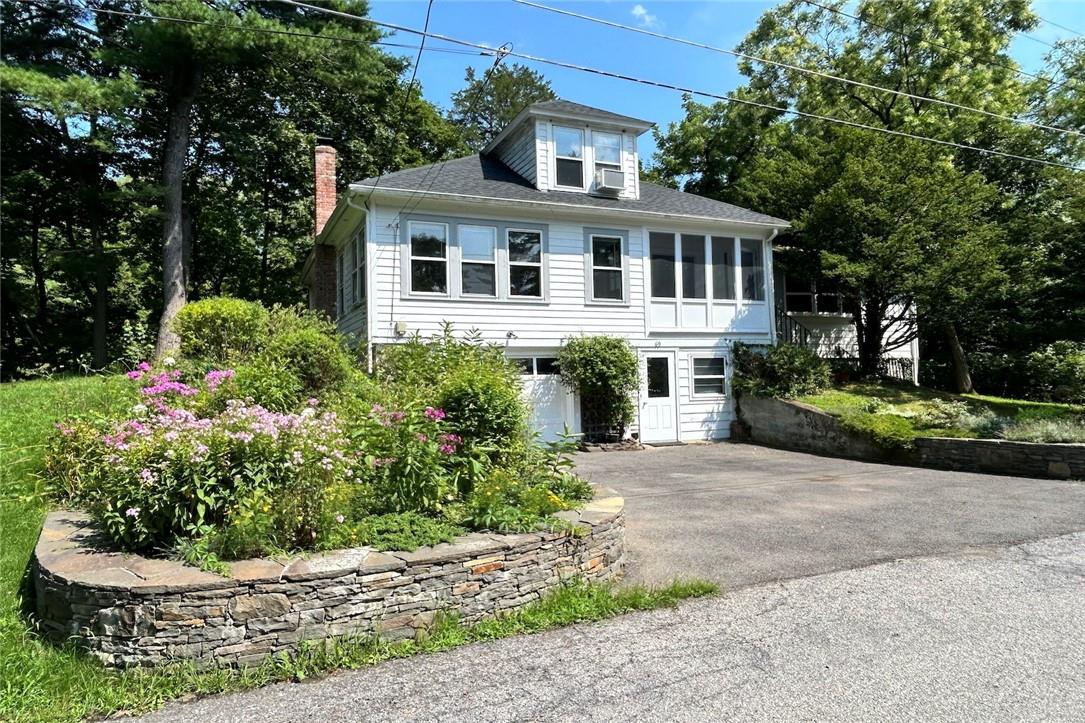 View of front of house with a garage, cooling unit, and a sunroom