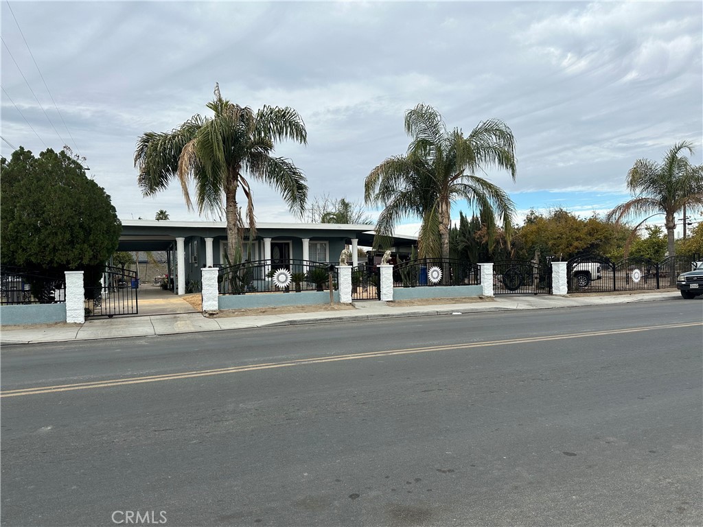 front view of house with a yard and palm trees