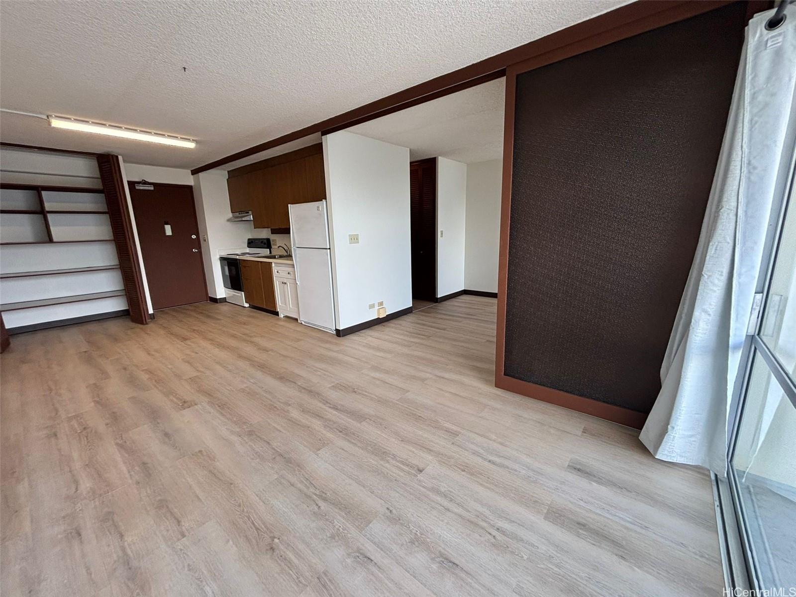 a view of a storage & utility room with refrigerator wooden floor