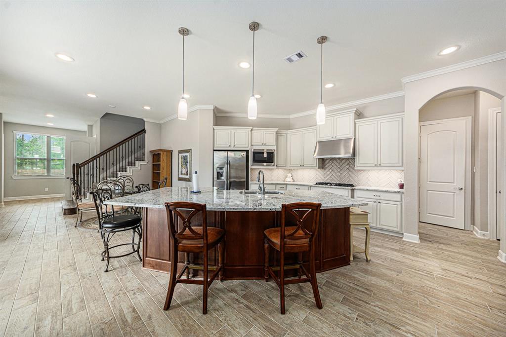 a kitchen with stainless steel appliances a dining table chairs stove and white cabinets