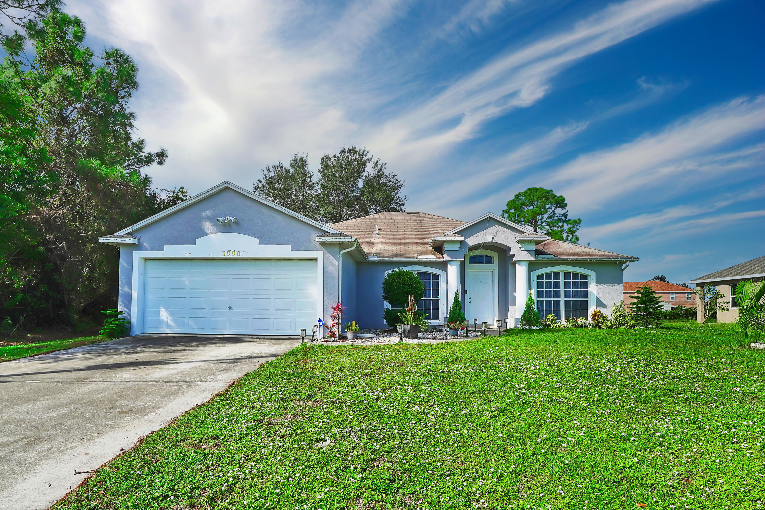 a front view of a house with a garden and trees