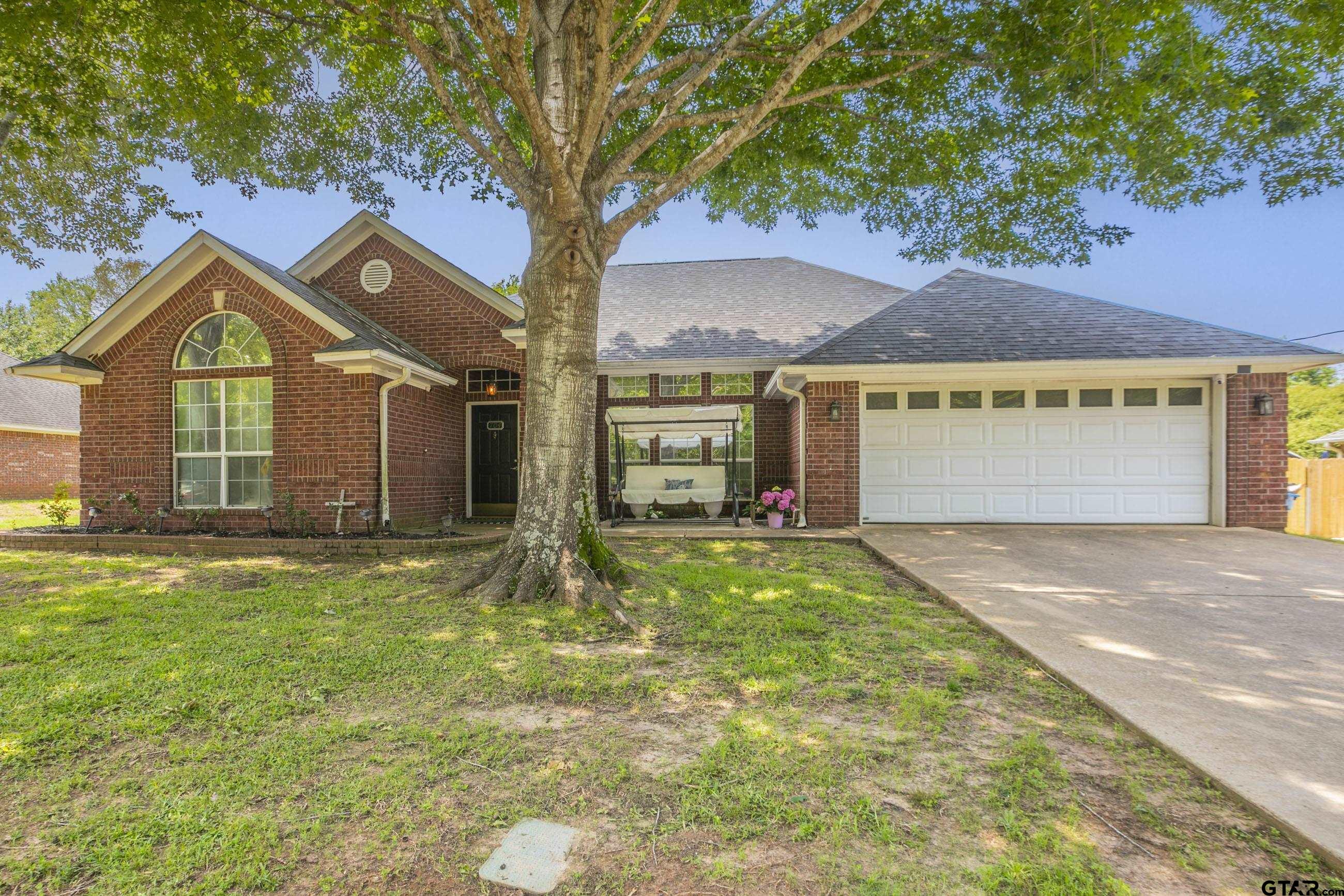 a view of yellow house with a big yard and large tree