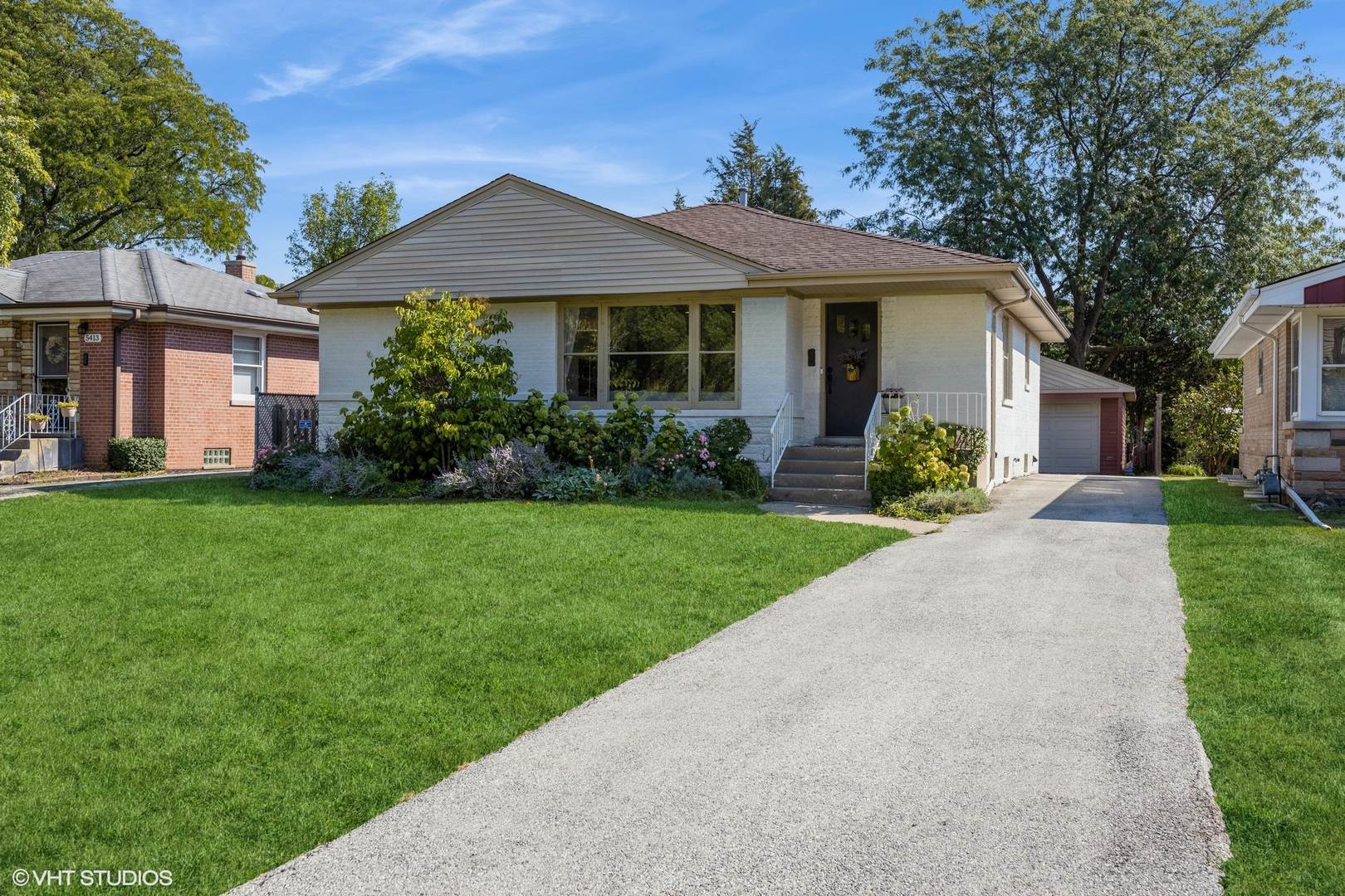 a front view of a house with a yard and potted plants